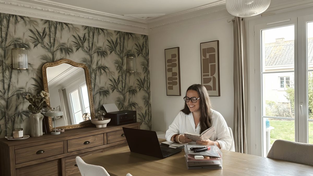 Sarah en consultation en visio, à sa table, un carnet à la main devant son ordinateur